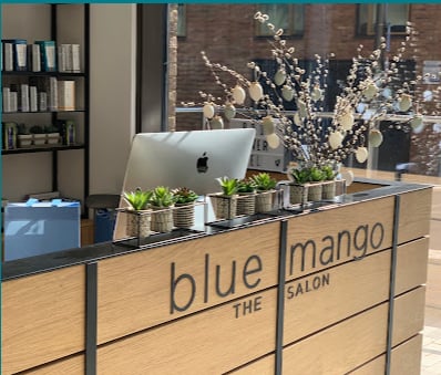 Blue Mango Salon reception desk with the salon name on its wooden counter